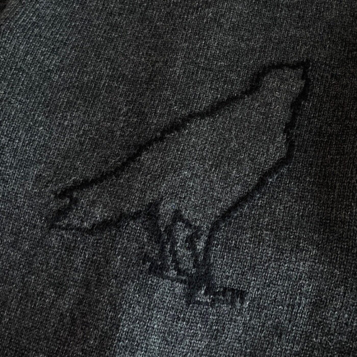 Tessuto grigio con ricamo minimalista di corvo, stile elegante e simbolico per moda e design.