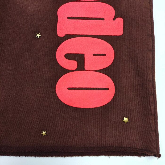 Tessuto decorativo marrone con lettere rosa e stelle doro, ideale per arredi e progetti creativi.