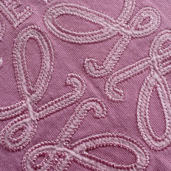 Tessuto rosa con ricami eleganti a loop, perfetto per moda e decorazioni sofisticate.