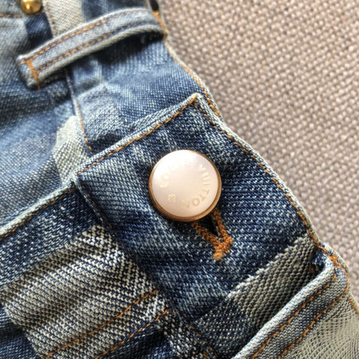 Dettaglio di Jeans con bottone metallico e cuciture contrasto su denim usurato.