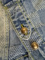 Denim con motivo checkered e bottoni in ottone dettagliati e cuciture gialle contrastanti.
