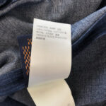 Etichetta in cotone e poliestere su denim di alta qualità, dettagli tessuti e composizione.