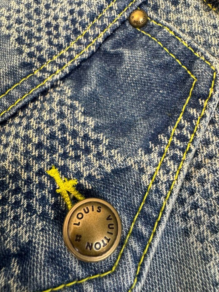 Jeans in denim houndstooth con bottone Louis Vuitton e cuciture gialle a contrasto.