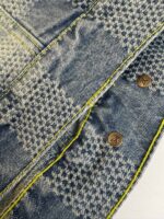 Jeans con motivo a quadri, cuciture gialle e bottoni in metallo brunito.