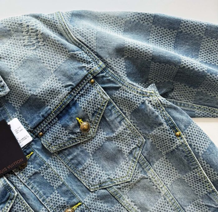 Giacca in denim chiaro con pattern a griglia, bottoni dorati e dettagli moderni.