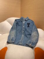 Giaccone in denim con emblema orsetto su poltrona moderna colorata, stile casual e trendy.