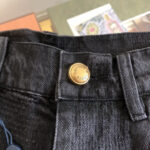 Jeans neri in denim con dettagli in ottone e cuciture eleganti, stile classico e moderno.