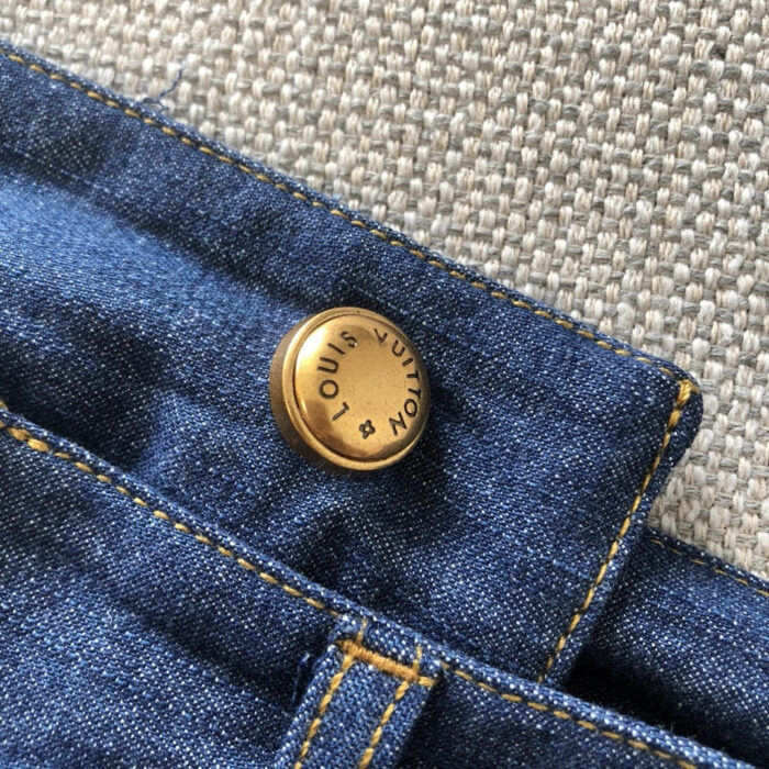 Jeans in denim con bottone dorato e cuciture beige di alta qualità.