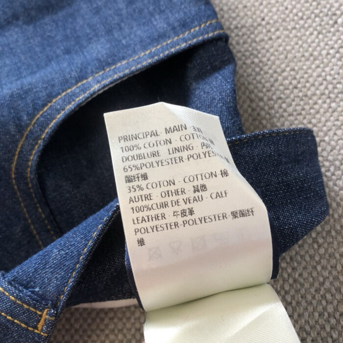 Etichetta di cura jeans in denim con materiali e istruzioni multilingue.