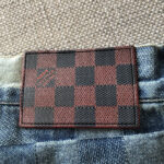 Etichetta in pelle checkerboard su jeans in denim blu, stile elegante e casual.