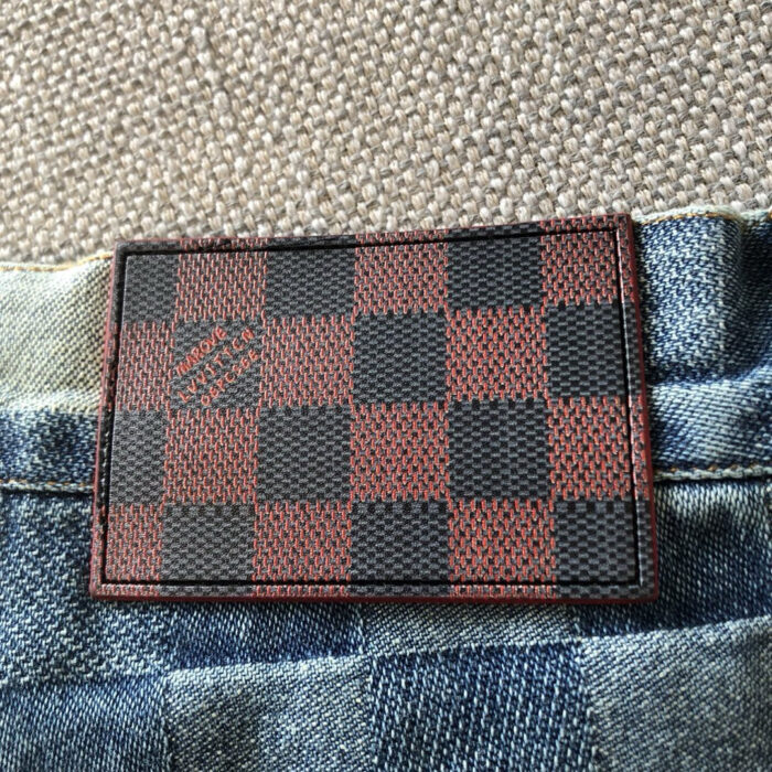 Etichetta in pelle checkerboard su jeans in denim blu, stile elegante e casual.