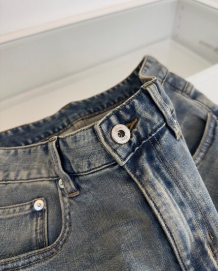 Jeans vintage blu chiaro con dettagli di cuciture contrastanti e cinturino in metallo.