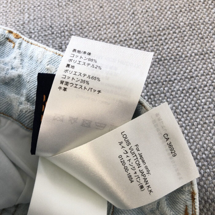 Etichette di jeans Louis Vuitton in denim con dettagli di cura e composizione.