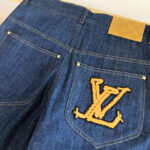Jeans blu con logo ricamato giallo e dettagli di stile moderno.