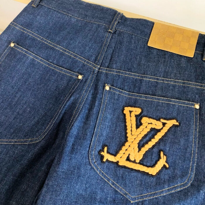 Jeans blu con logo ricamato giallo e dettagli di stile moderno.