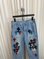 Jeans chiari con croci colorate artistiche su rastrelliera, stile casual e creativo.