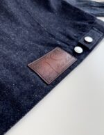 Grembiule in denim con dettagli in pelle e bottoni bianchi per stile e praticità.