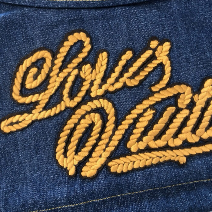 Denim blu con ricamo Louis Vuitton in giallo oro, stile elegante e di alta qualità.