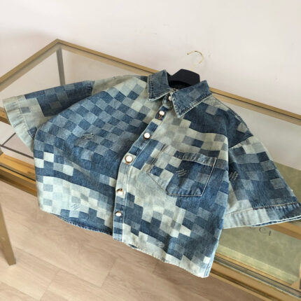 Camicia cropped in jeans patchwork con bottoni metallici e tasca frontale, stile casual e moderno.