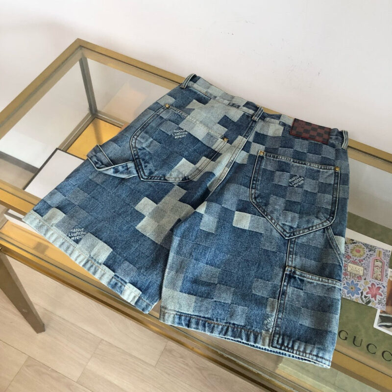 Pantaloncini in denim patchwork su tavolo di vetro, stile moderno e casual.