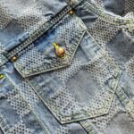 Tasca in denim chiara con bottone in ottone e dettagli di cuciture colorate.