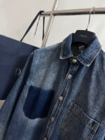 Camicia di denim scura con tasca contrasto, accompagnata da shopping bag blu di moda.
