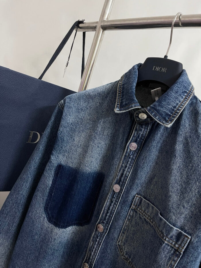 Camicia di denim scura con tasca contrasto, accompagnata da shopping bag blu di moda.