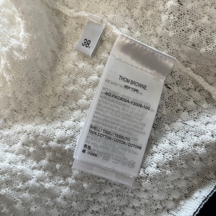 Etichetta di lusso Thom Browne in tessuto cotone elastan, dettagli eleganti e qualità premium.