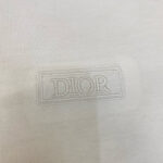 Logo Dior in rilievo su tessuto di lusso neutro ed elegante, simbolo di alta moda raffinata.