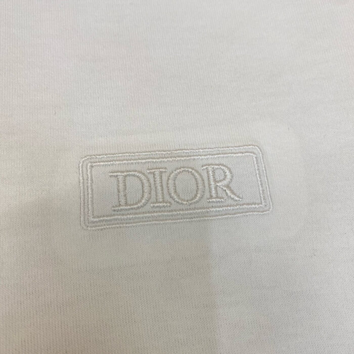 Logo Dior in rilievo su tessuto di lusso neutro ed elegante, simbolo di alta moda raffinata.