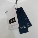 Tag Dior su maglietta di lusso con logo nero e dettagli di cura.