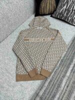 Felpa Dior beige con logo, stile moderno, su divano elegante e capiente.