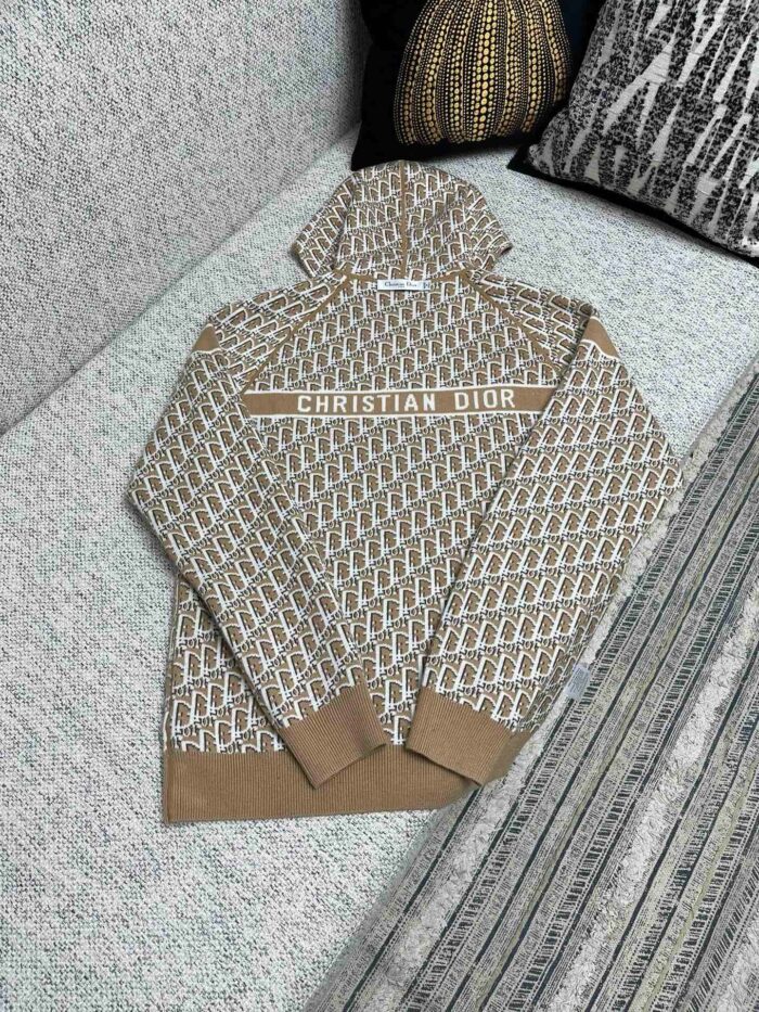 Felpa Dior beige con logo, stile moderno, su divano elegante e capiente.