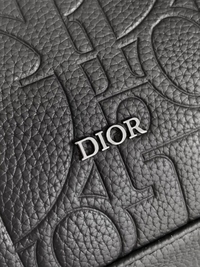 Pelle nera Dior con logo in metallo e dettagli embossati, simbolo di lusso e raffinatezza.