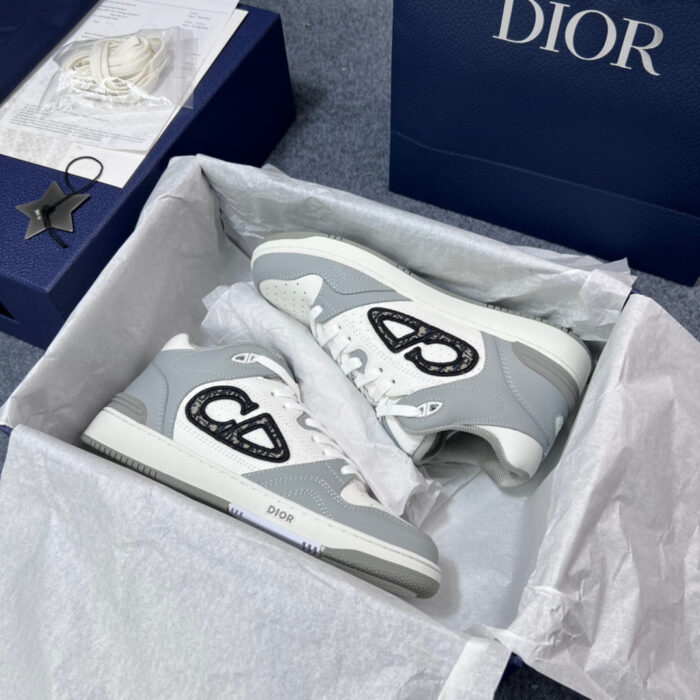Sneakers Dior grigio e bianco in scatola di lusso, stile elegante e dettagli raffinati.