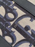 Tessuto Dior di lusso con motivo stilizzato, logo metallizzato e bordo verde raffinato.
