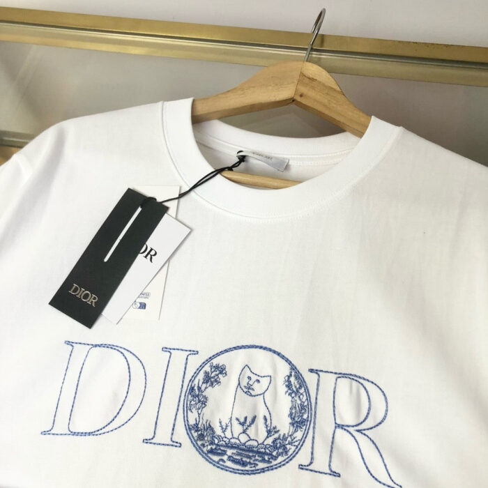 Maglietta Dior bianca con logo blu e dettagli eleganti, stile raffinato e di lusso.
