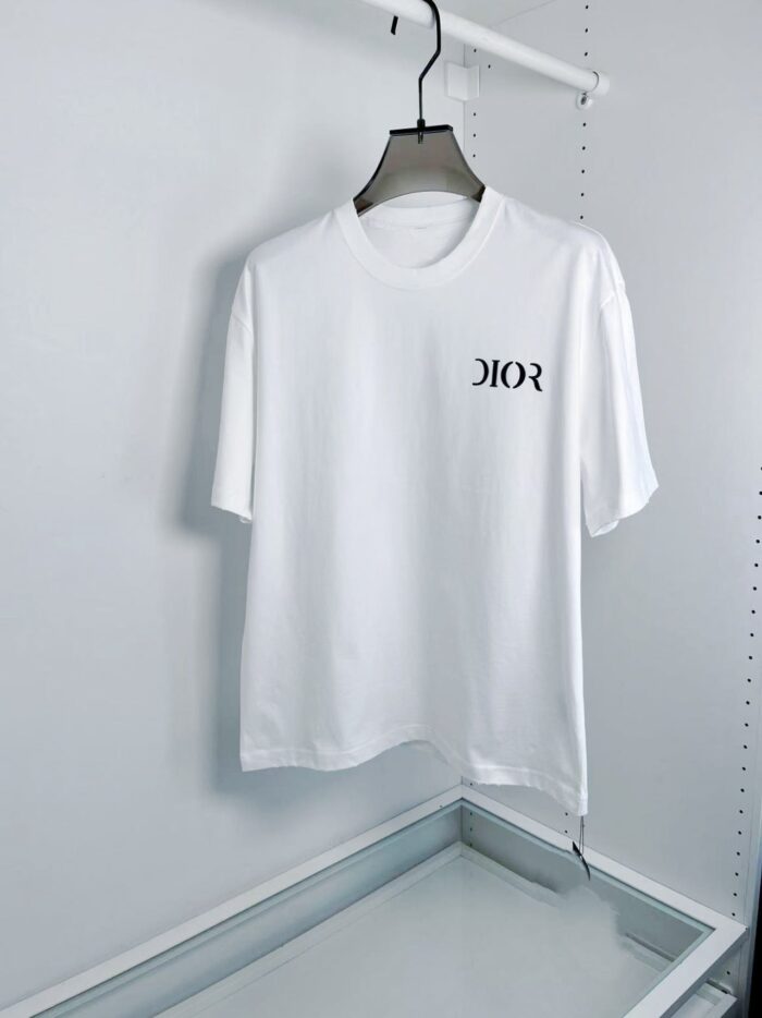 Maglietta bianca Dior con logo elegante, stile minimalista, su appendiabiti moderno.