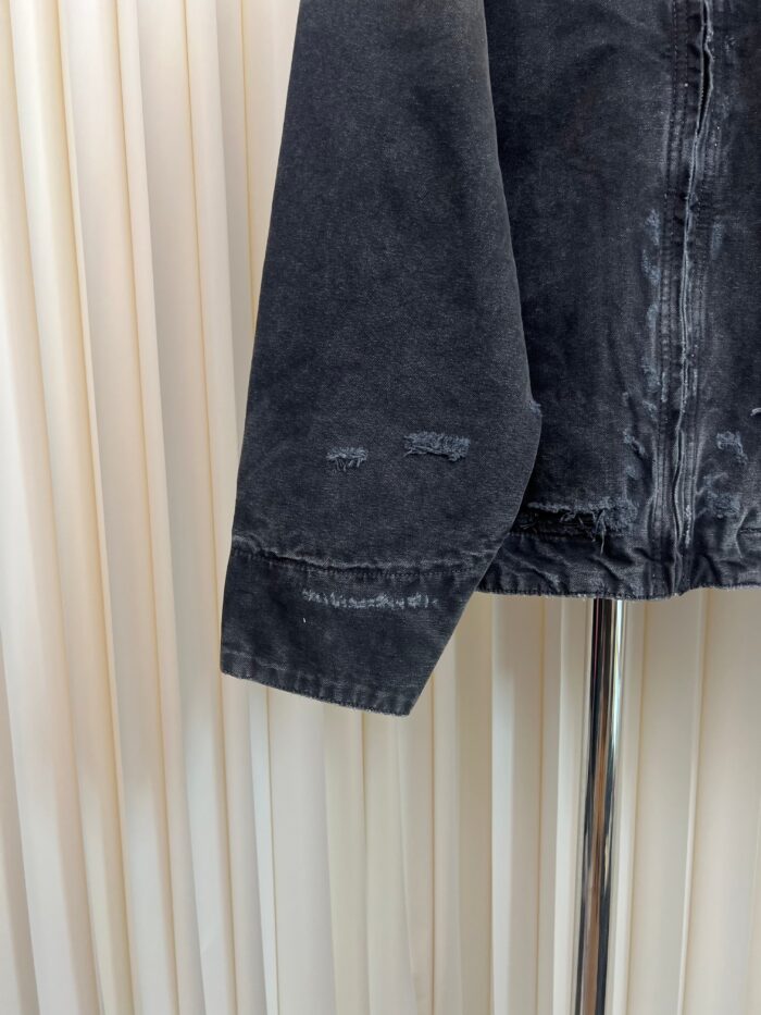 Dettaglio di una giacca in denim vintage con polsino sfilacciato e stile retrò.