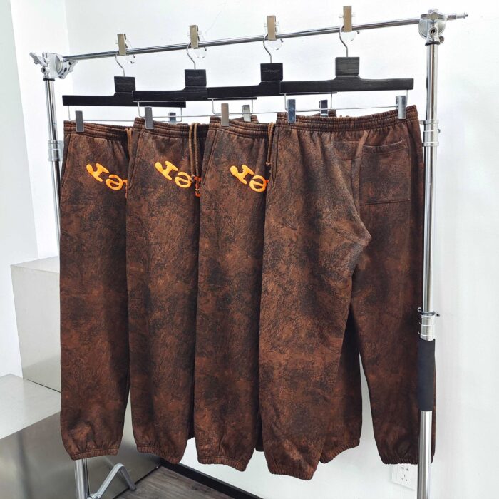 Pantaloni marroni in stile pelle distressed con logo YET giallo, moda streetwear moderna e di tendenza.