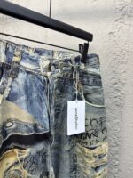 Jeans distressed con dettagli artistici, patch colorati e scritte graffiti, stile urbano e moderno.