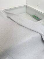Tessuto leggero e drappeggiato su superficie di vetro, atmosfera minimalista ed elegante.