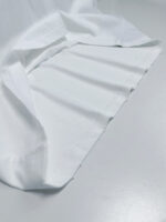 Tela bianca morbida e elegante con pieghe delicatamente drappeggiate su sfondo neutro.