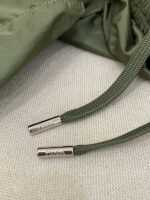 Cordino in oliva con aglet in metallo su giacca sportiva leggera.