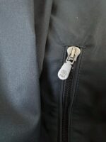 Chiusura lampo in metallo su giacca impermeabile di alta qualità, dettaglio resistente e moderno.