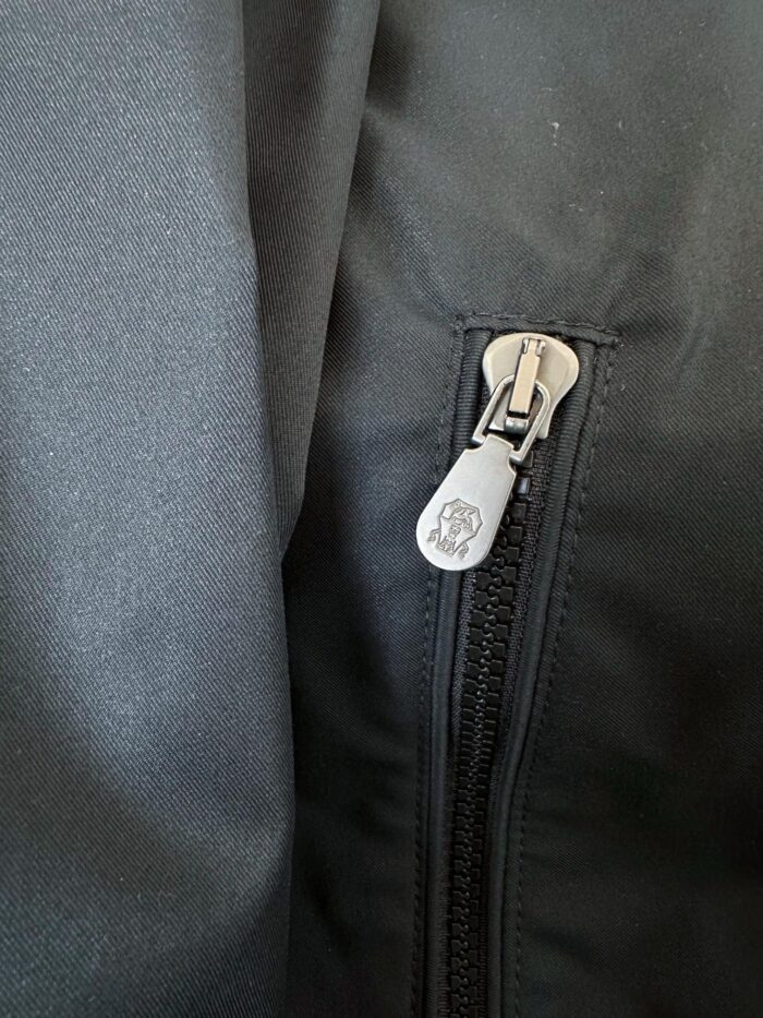 Chiusura lampo in metallo su giacca impermeabile di alta qualità, dettaglio resistente e moderno.