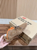 Sneakers New Balance in suede marrone con lacci arancioni e scatola Made in Italy elegante.