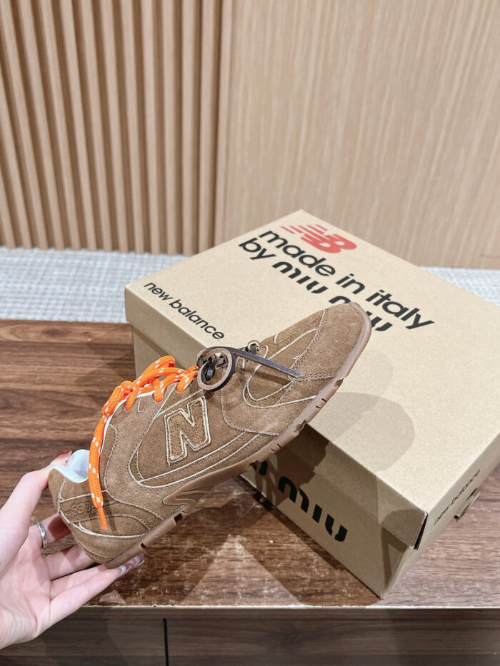 Sneakers New Balance in suede marrone con lacci arancioni e scatola Made in Italy elegante.