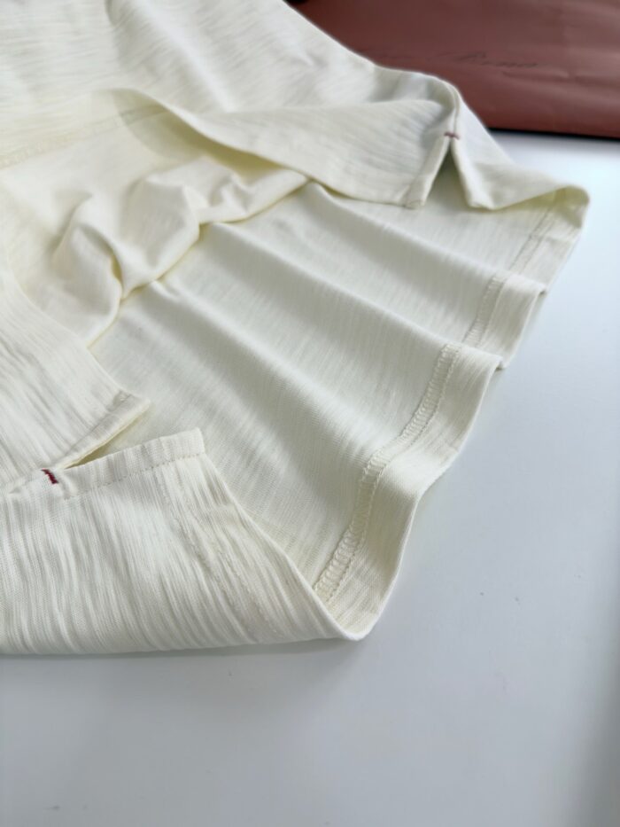 Tessuto crema con pieghe delicate, dettagli artigianali e contrasti di colore caldo.