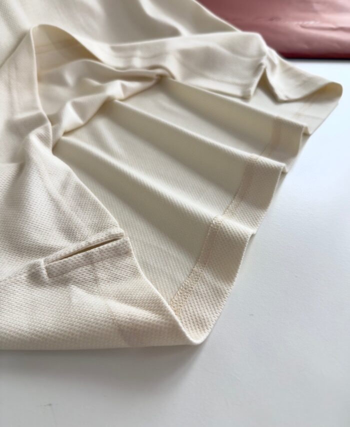 Tessuto avorio con pieghe eleganti e texture raffinata per abbigliamento di stile.